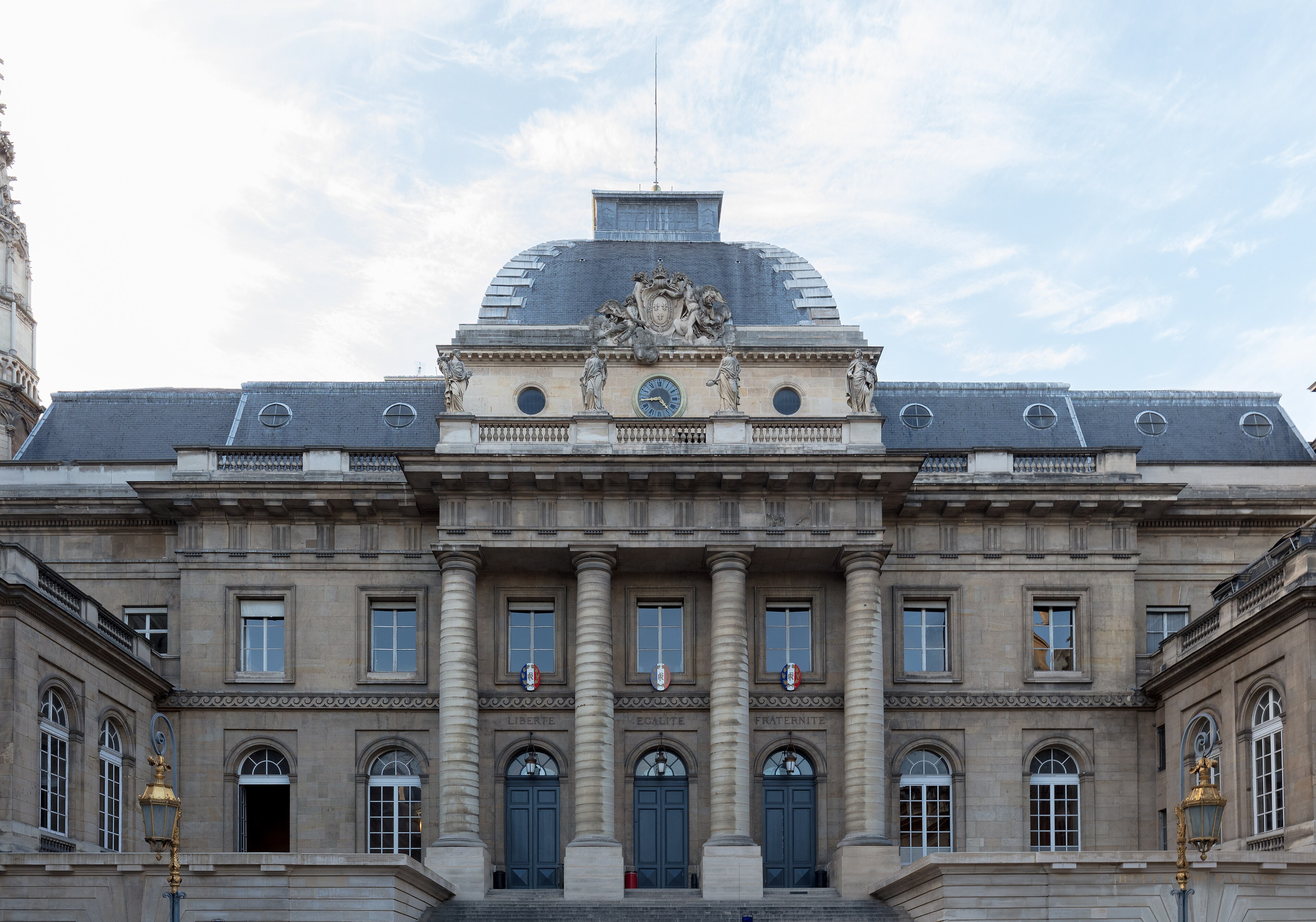 Façade du Palais de Justice de Paris : colonnes, horloge, devises Liberté Égalité Fraternité au-dessus des portes.