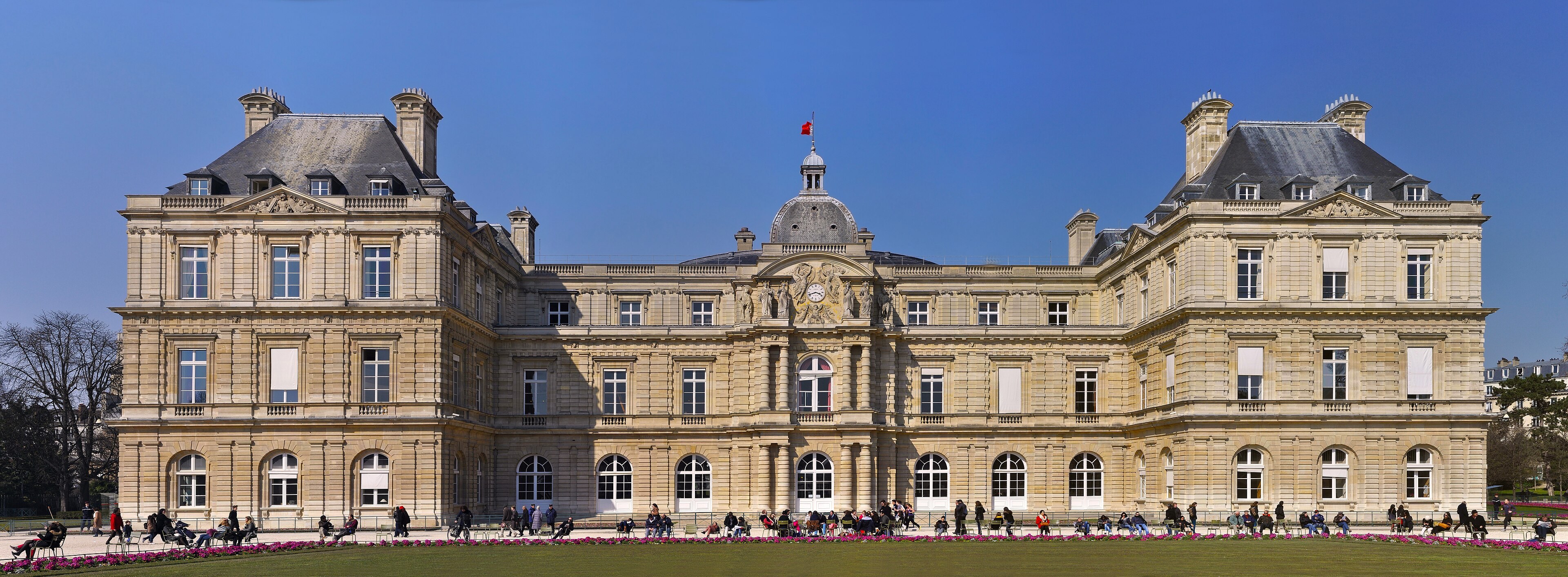 Façade jardin du Palais du Luxembourg, dôme central, pelouse et promeneurs au premier plan.
